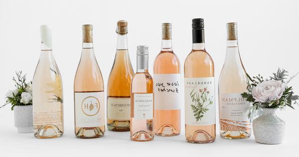 Seven bottles of Rosé with small cups of flowers on either end